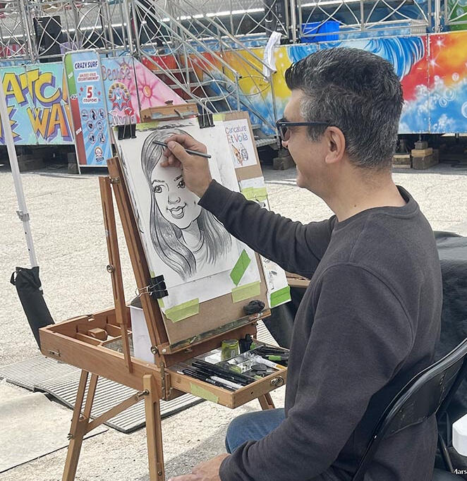 Caricature Artist Drawing Caricatures at an amusement fair Caricature artist sketching a guest at an amusement fair